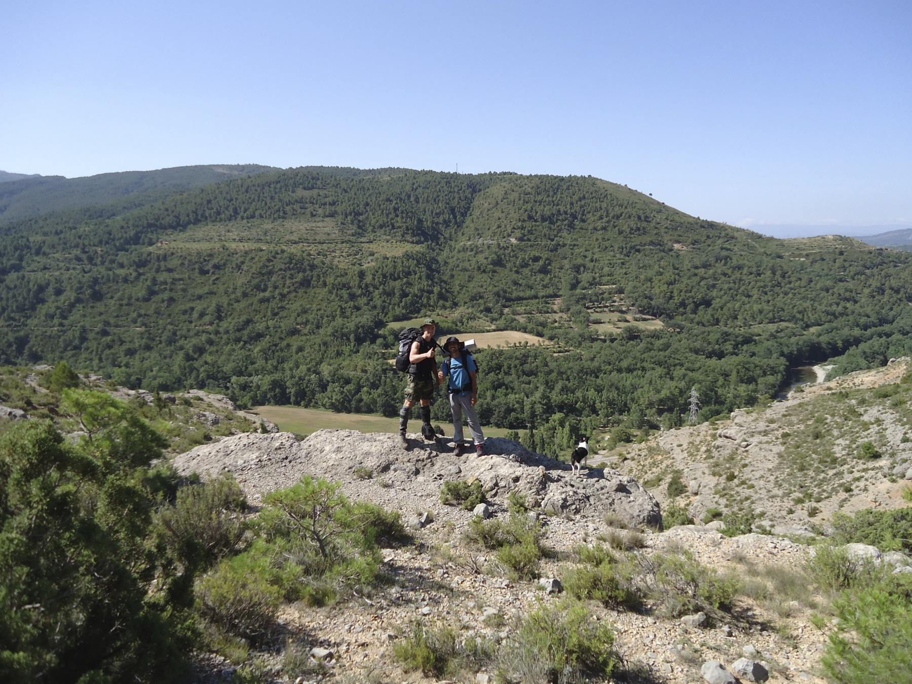 Deelnemers van de Study of Origin met rugzakken op een rotsrichel boven een dal in de Spaanse Pyreneeën