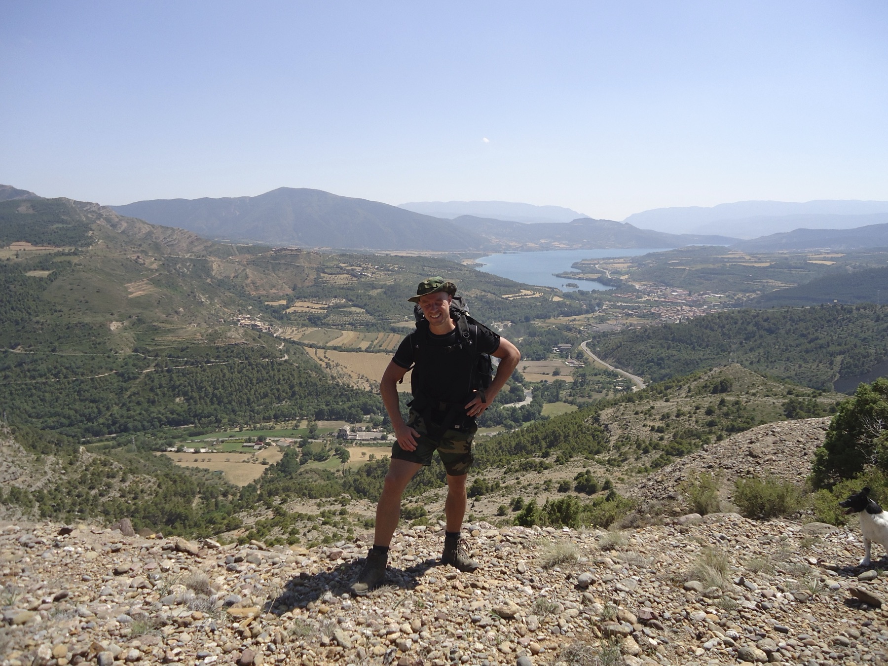 Jan Willem met rugzak kijkt uit over een dal met stuwmeer in de Spaanse Pyreneeën